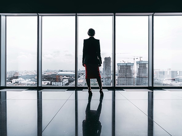 Woman in office looking out of a window at cityscape